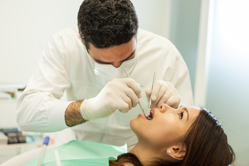 Obraz na płótnie Canvas caucasian dentist is visiting an asian woman