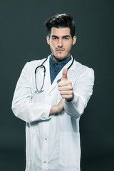 Doctor making positive thumb gesture over grey background