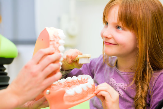 Zahnärztin erklärt Mädchen Zähneputzen 