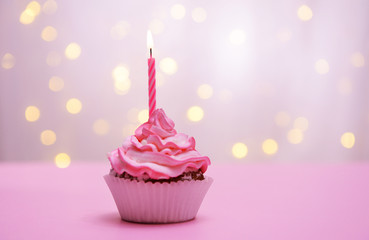 Delicious birthday cupcake on table on light background