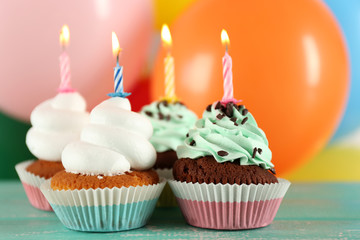 Delicious birthday cupcakes on table on bright background