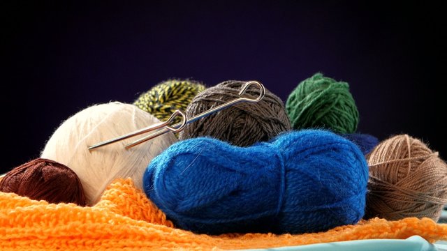 Colorful yarn balls with spokes on orange scarf, black
