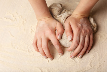 Making dough by female hands on wooden table background