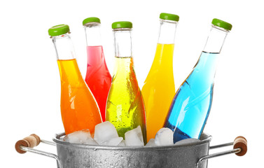 Bottles of tasty drink in metal bucket with ice isolated