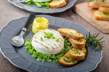 Fototapeta na wymiar Grilled camembert with herbs, baquettes