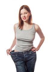 Obraz premium young smiling woman in big jeans showing successful weight loss