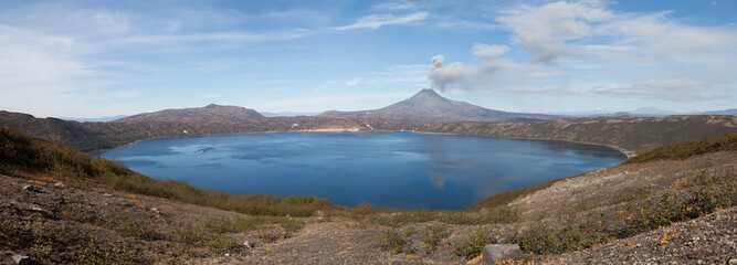 Volcanic eruption. Smoke over mountain lake.