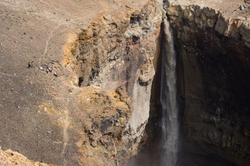 A group of tourists is on the edge of the waterfall