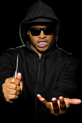 thug holding a knife coming out of the shadows