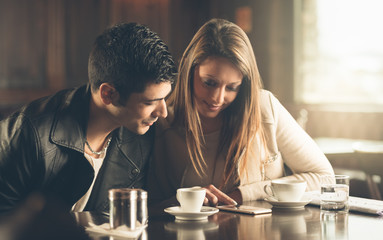 Friends at the cafe using a mobile phone