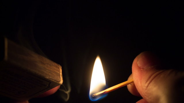 Close-up of hands lighting a match