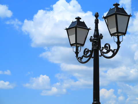 Old street decorated lamppost against cloudy blue sky