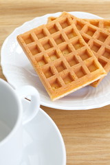 Delicious sweet waffle in white plate on wood background