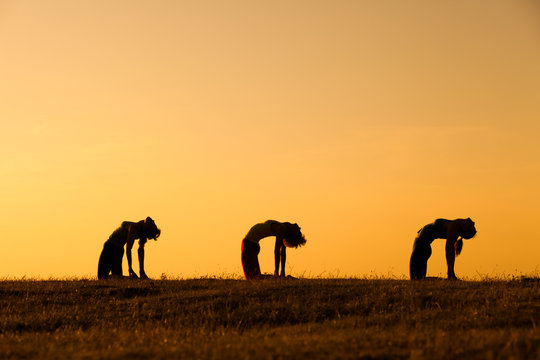 Silhouettes of girls practicing yoga in sunset