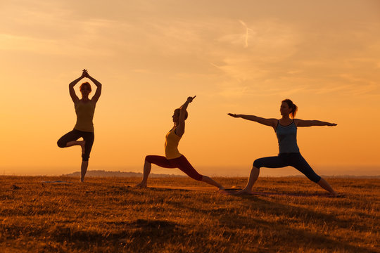 Silhouette of girls practicing yoga in sunset