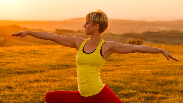 Woman practicing yoga in sunset