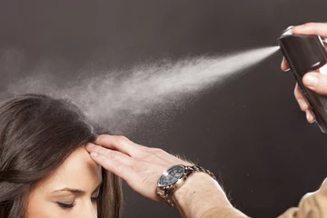 Foto auf Acrylglas Friseur Friseur trägt Haarspray auf die Haare seiner Kunden auf