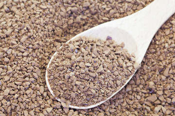 Granules of instant coffee in wooden spoon