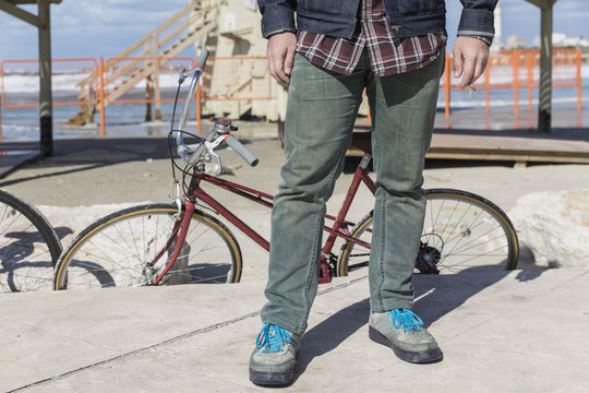 Closeup of man&rsquo;s legs standing inform of a vintage bicycle