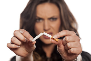 Angry young woman hold a broken cigarette on  a white background