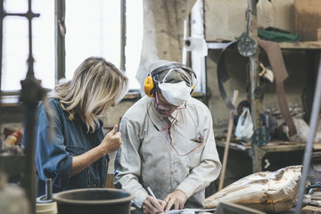 2 craftsman, woman and man talking in an artist workshop