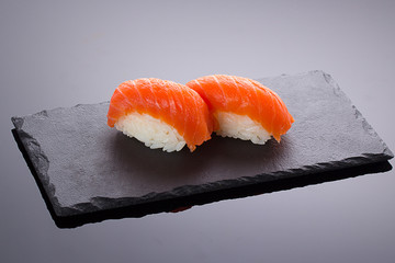Salmon sushi nigiri on a stone plate over black backround
