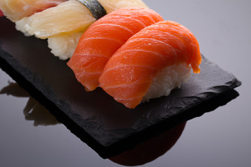 Sushi nigiri set on a stone plate over black background