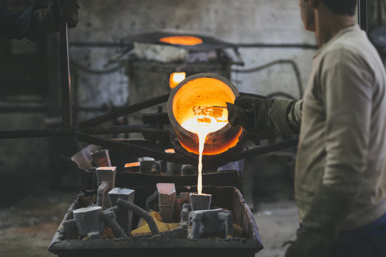 Man pouring melted bronze into molds using a crucible