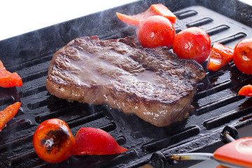 Stake with cherry tomato on a hot grill