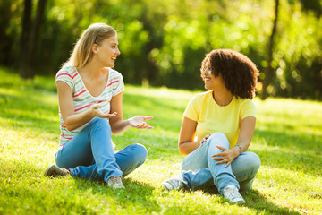 Naklejka na ściany i meble Two young women talking in park