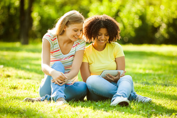 Fototapeta premium Two young women using tablet in park
