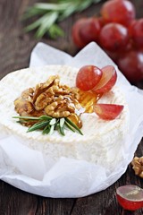 Camembert with walnuts and honey on a rustic wooden table.