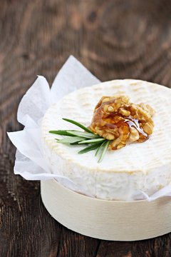Camembert with walnuts and honey on a rustic wooden table.