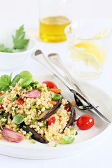 Bulgur salad with vegetables and herbs on a white background.