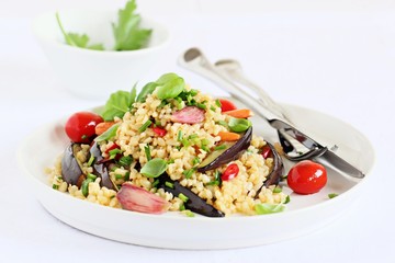 Bulgur salad with vegetables and herbs on a white background.