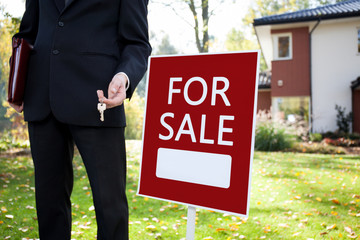 Estate agent with keys and sign