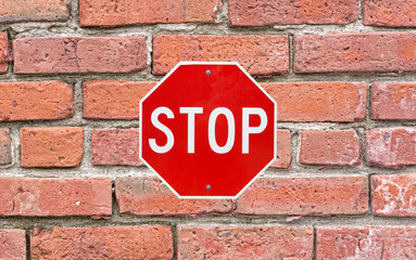 Bright stop sign attached to large brick siding