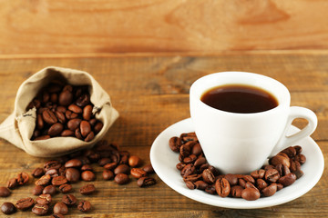 Cup of coffee with beans on rustic wooden background