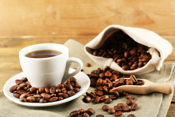 Cup of coffee with beans on rustic wooden background