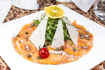 Slices of salmon with herbs and cheese on a white plate
