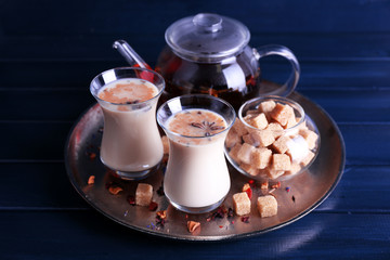 Black tea with milk in glasses and teapot with lump sugar