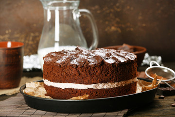 Delicious chocolate cake on table on brown background
