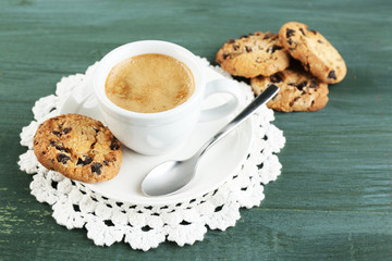 Cup of coffee and tasty cookie on color wooden background