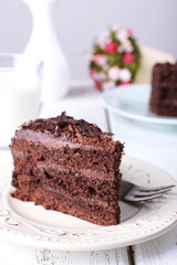 Sliced tasty chocolate cake in plate on wooden table, closeup