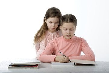 Fototapeta premium Little girls read books at the table on white