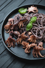 Black rice vermicelli with octopuses in a frying pan, close-up