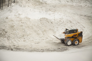 Yellow bulldozer removing large amounts of snow