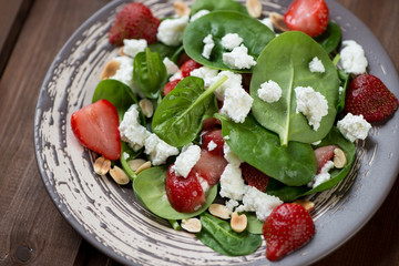 Salad with spinach leaves, strawberries and cheese, close-up