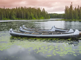 Zelfklevend Fotobehang Canoes floating on a peaceful lake at sunset, Quebec, Canada © SimoneGilioli