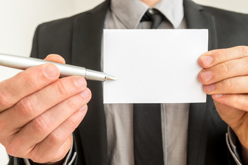 Businessman holding out a blank card and pen - obrazy, fototapety, plakaty